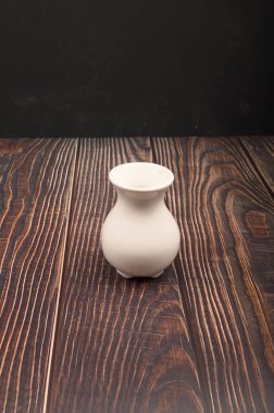 White ceramic vase in Chinese style on a wooden background. Close up.