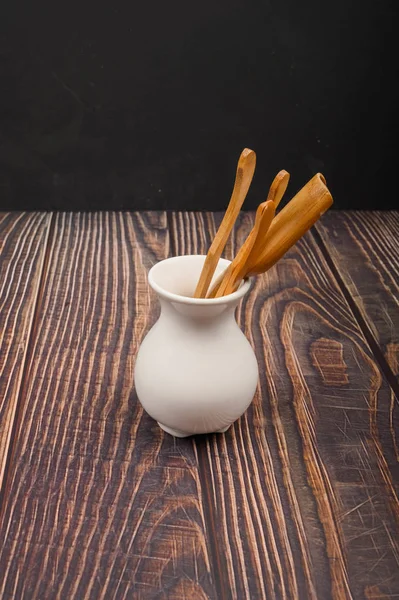 Devices for traditional Chinese tea drinking made of bamboo in a white ceramic vase in the Chinese style on a wooden background. Close up. — Stockfoto