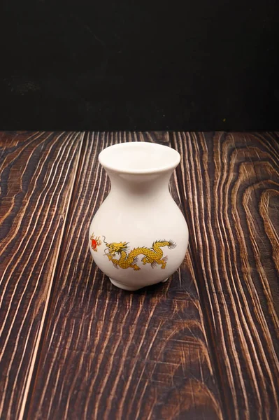 Biały ceramiczny wazon z chińskim wzorem na drewnianym tle. Zamknij się.. — Zdjęcie stockowe
