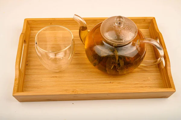 Chá de flor fabricado em um bule de vidro e um copo em uma bandeja de madeira em um fundo branco. Fechar . — Fotografia de Stock