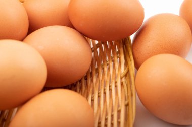 Hasır bir sepette beyaz bir arka planda tavuk yumurtası. Kapat.