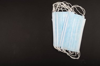 Siyah arka planda tek kullanımlık tıbbi maskeler. Bulaşıcı hastalıklara karşı bireysel koruma. Kapat.