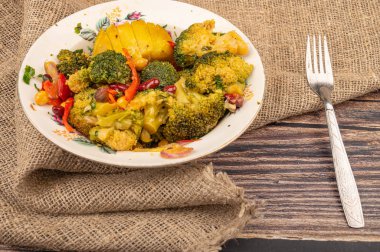 Beyaz seramik tabakta sebze salatası ve kaba ev yapımı kumaştan yapılmış çatal. Kapat.