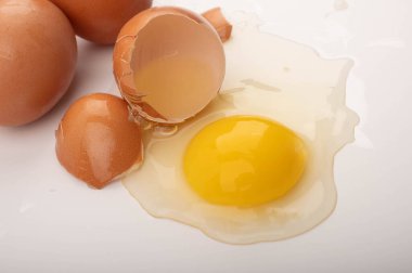 Kırık tavuk yumurtası ve yumurtalar beyaz arka plana saçılmış. Kapat.