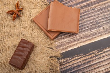 Eski bir fincan tutacağında bir bardak çay, yıldız anason ve kaba kumaştan yapılmış bir arka planda esmer şeker. Kapat.