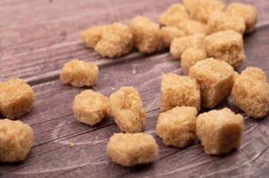 Tahta zemine saçılmış esmer şeker parçaları. Kapat.