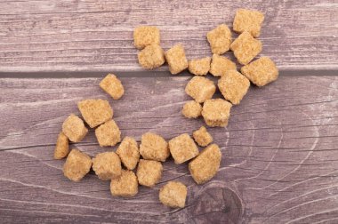 Tahta arka planda kahverengi kamış şekeri parçaları. Kapat.