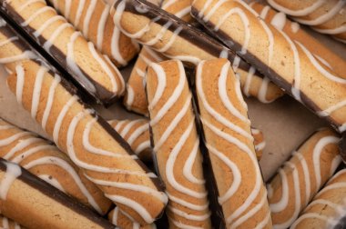 Kırmızı seramik çay fincanı, kurabiyeler ve tahta arka planda kamış şekeri parçaları. Kapat.