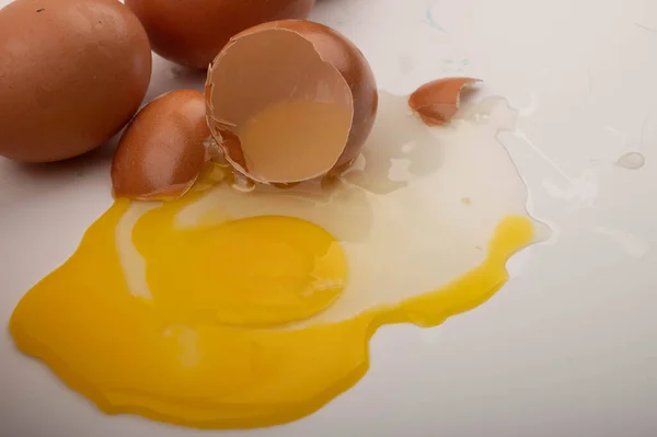 Un uovo di pollo rotto e uova sparse su uno sfondo bianco. Da vicino. . — Foto Stock