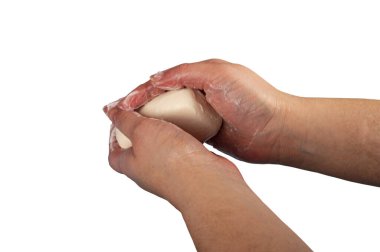 Birisi bir parça tuvalet sabunuyla ellerini sabunluyor. Sık sık sabunla el yıkama COVID-19 enfeksiyonunun önlenmesidir. Kapatın. Beyaz arkaplanda izole et