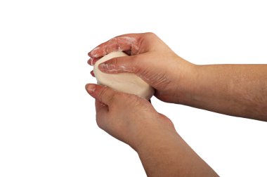 Birisi ellerini bir parça tuvalet sabunuyla sabunluyor. Beyaz arka planda izole edin. Kapatın. Sık sık sabunla el yıkama COVID-19 enfeksiyonunun önlenmesidir.