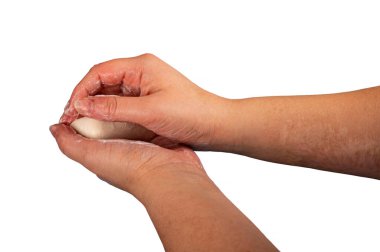 Birisi bir parça tuvalet sabunuyla ellerini sabunluyor. Kapatın. Sabunla düzenli el yıkama COVID-19 enfeksiyonunun önlenmesidir. Beyaz arkaplanda izole et