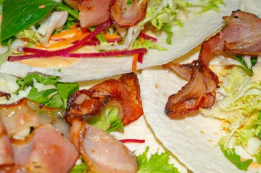 Ev yapımı Shawarma 'nın temelinde yapraklı salata, dilimlenmiş sebze, sos ve kızarmış pastırma dilimleri yer alıyor. Kapat.