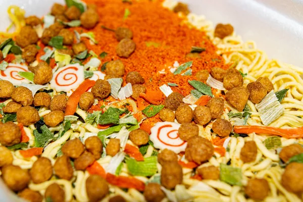 Instant noodles with spices, dried vegetables and freeze-dried meat. Surface texture close-up