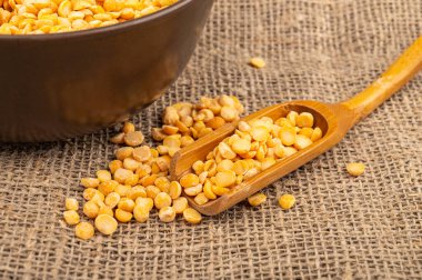 Çuval bezelyeli, ahşap kaşıklı bezelye kabarık desenli bir arka planda. Çorba ve yulaf lapası yapmak için geleneksel mısır gevreği. Kapat.