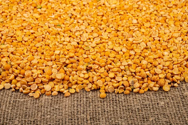 Yellow split peas scattered on a background of coarse-textured burlap. Traditional cereals for making soups and porridge. Close up — Stock Image Yellow Split Peas Scattered Background Coarse Textured Burlap Traditional Cereals Royalty Free Stock Photos