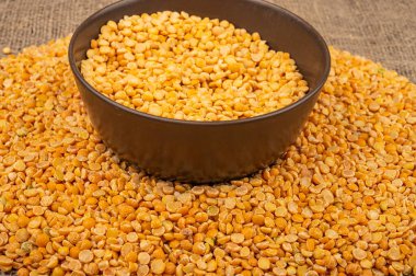 Seramik bir kasede sarı bezelye ve kabarık desenli çuval bezelyesine saçılmış mısır ezmesi. Çorba ve yulaf lapası yapmak için geleneksel mısır gevreği. Kapat.