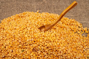 Kabataslak desenli çuval bezelyesine saçılmış sarı bezelyeler. Çorba ve yulaf lapası yapmak için geleneksel mısır gevreği. Kapat.