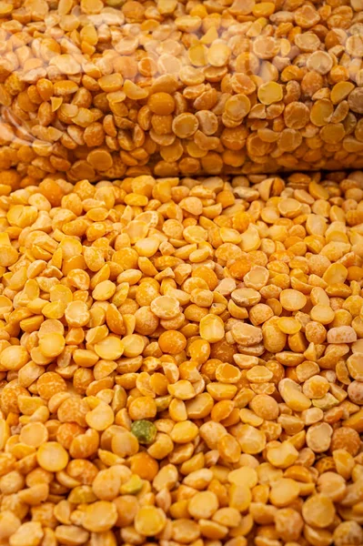 Yellow split peas in a plastic bag and cereal in bulk on a background of burlap with a rough texture. Traditional cereals for making soups and porridge. Close up — Stock Image Yellow Split Peas Plastic Bag Cereal Bulk Background Burlap Rough Stock Picture