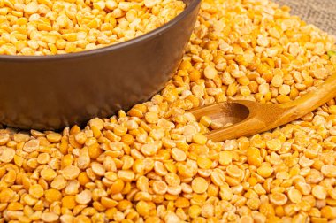 Seramik bir kasede sarı bezelye ve kabarık desenli çuval bezelyesine saçılmış mısır ezmesi. Çorba ve yulaf lapası yapmak için geleneksel mısır gevreği. Kapat.