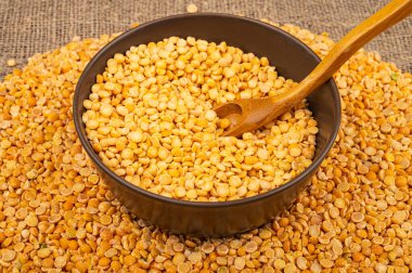 Seramik bir kasede sarı bezelye ve kabarık desenli çuval bezelyesine saçılmış mısır ezmesi. Çorba ve yulaf lapası yapmak için geleneksel mısır gevreği. Kapat.