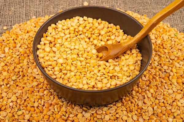 Seramik bir kasede sarı bezelye ve kabarık desenli çuval bezelyesine saçılmış mısır ezmesi. Çorba ve yulaf lapası yapmak için geleneksel mısır gevreği. Kapat.