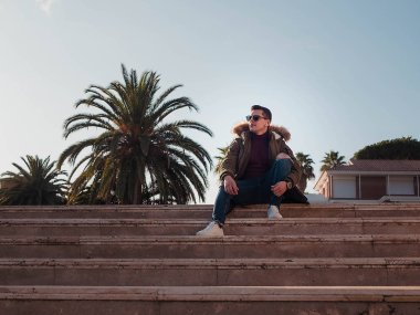 Güneşli bir kış gününde merdivende oturan adam