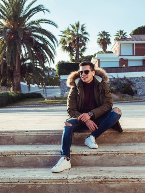 Güneşli bir kış gününde merdivende oturan adam