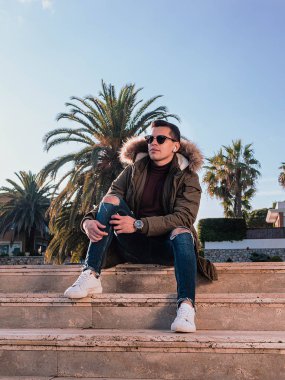 Güneşli bir kış gününde merdivende oturan adam