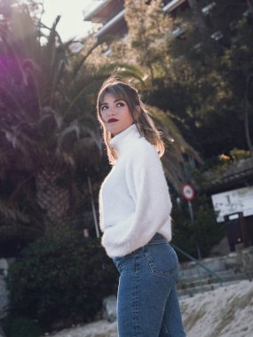 İspanyol kız arkasında palmiye ağacı ve güneş ışığıyla poz veriyor