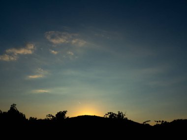 Tepelerin ve çalıların ardında gün batımı
