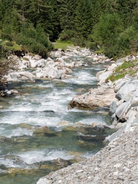 Alplerde taştan kıyıları olan dağ deresi