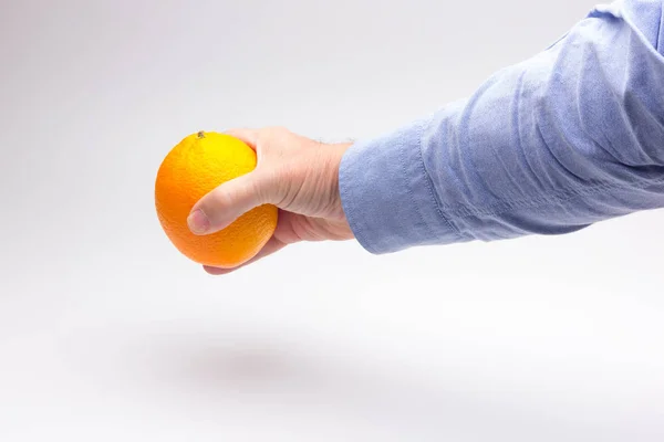 Naranja en la mano de una persona adulta, preparando un jugo — Foto de Stock