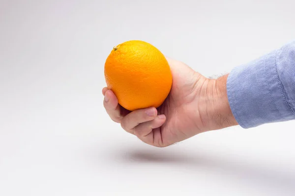 Orange in the hand of an adult person, preparing a juice — Stock Photo, Image