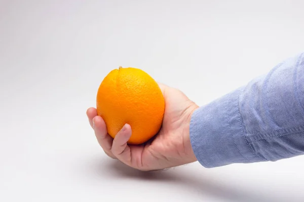 Orange in the hand of an adult person, preparing a juice — Stockfoto
