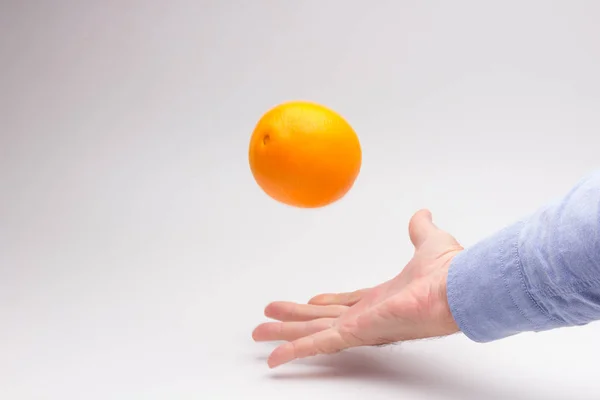 Апельсин в руке взрослого человека, готовящего сок — стоковое фото