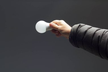 Enerji tasarrufu ampulü bir yetişkinin elinde.