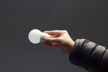 Enerji tasarrufu ampulü bir yetişkinin elinde.