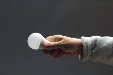 Enerji tasarrufu ampulü bir yetişkinin elinde.