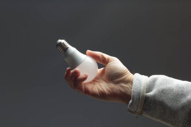 Enerji tasarrufu ampulü bir yetişkinin elinde.