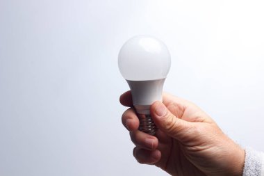 Enerji tasarrufu ampulü bir yetişkinin elinde.