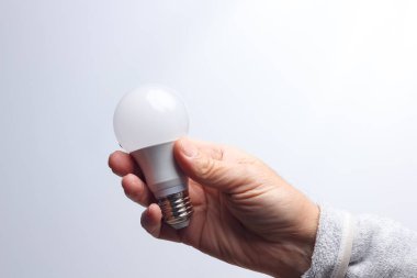 Enerji tasarrufu ampulü bir yetişkinin elinde.