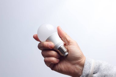 Enerji tasarrufu ampulü bir yetişkinin elinde.