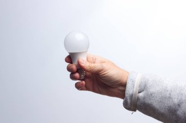 Enerji tasarrufu ampulü bir yetişkinin elinde.