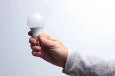 Enerji tasarrufu ampulü bir yetişkinin elinde.