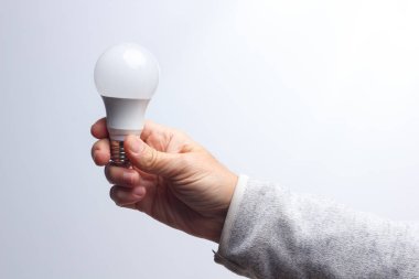 Enerji tasarrufu ampulü bir yetişkinin elinde.