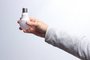 Enerji tasarrufu ampulü bir yetişkinin elinde.
