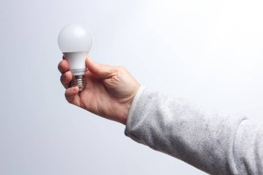 Enerji tasarrufu ampulü bir yetişkinin elinde.