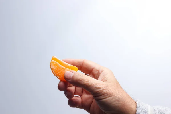 Tangerine slice in the hand of an adult person