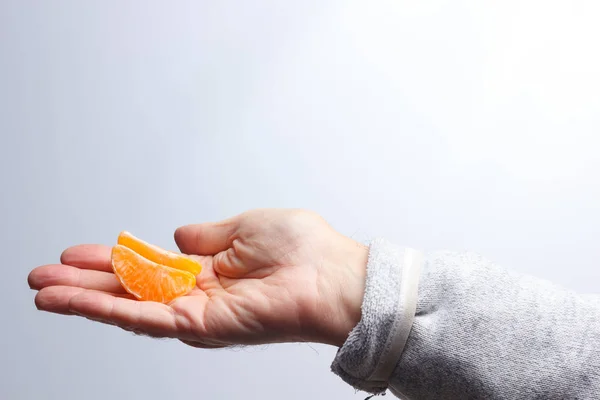 Corte de mandarina en la mano de una persona adulta — Foto de Stock